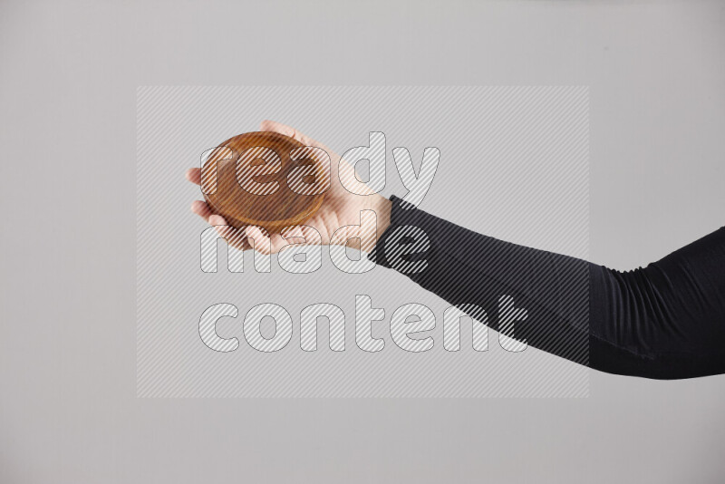 A woman in black abaya holding different wooden essentials in different positions