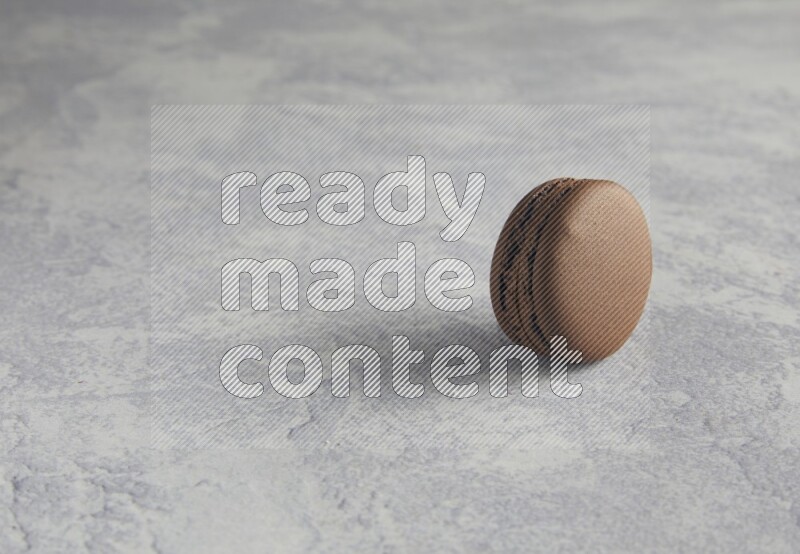 45º Shot of Brown Dark Chocolate macaron on white  marble background