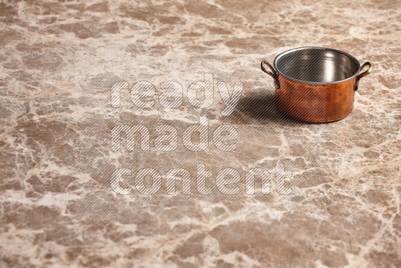 A small copper pot on beige marble background
