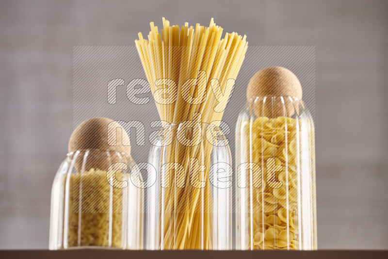 Raw pasta in glass jars on beige background