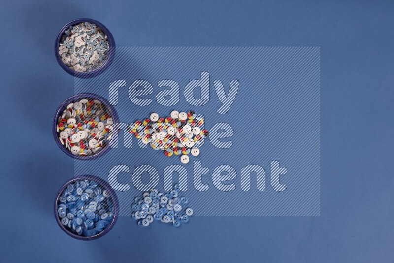 أوعية فخارية متعددة الألوان مليئة بالأزرار الملونة على خلفية زرقاء