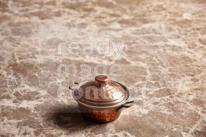 A small copper pot on beige marble background
