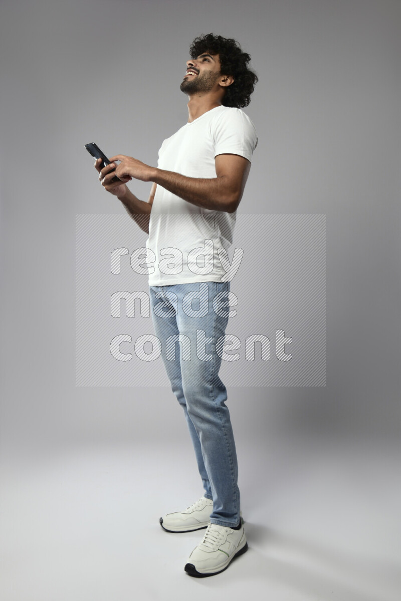 A man wearing casual standing and browsing on the phone on white background