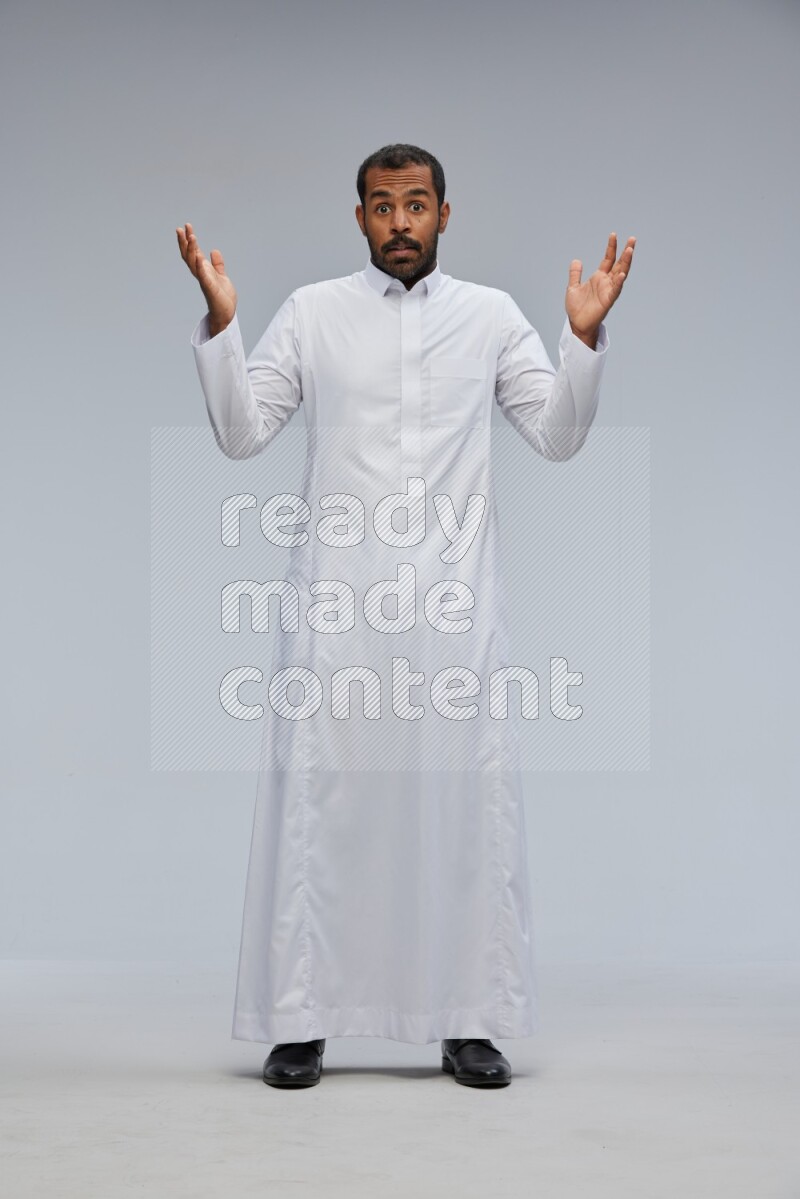 Saudi man Wearing Thob standing interacting with the camera on Gray background
