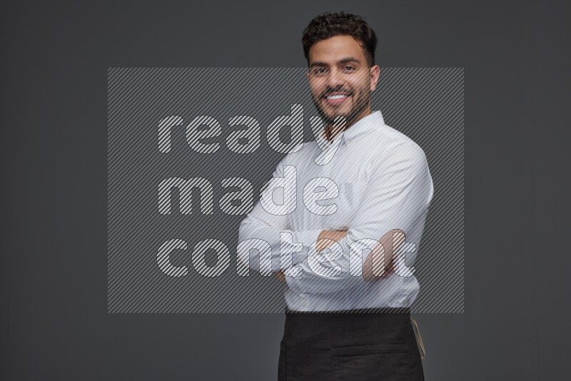 A man wearing smart casual and apron standing and making multi poses eye level on a gray background