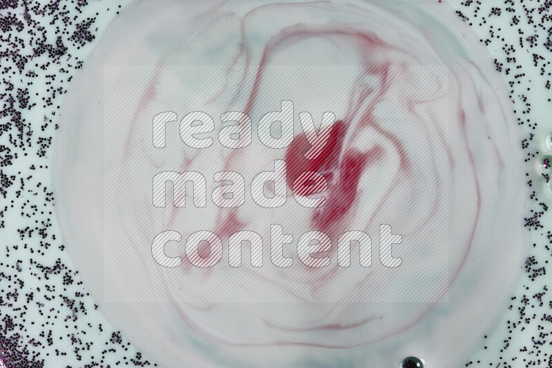 A close-up of swirls of red with sparkling purple glitter scattered on green background