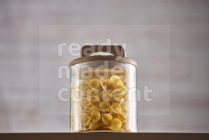 Raw pasta in glass jars on beige background