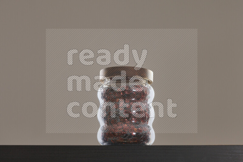 Sequins in a glass jar on black background