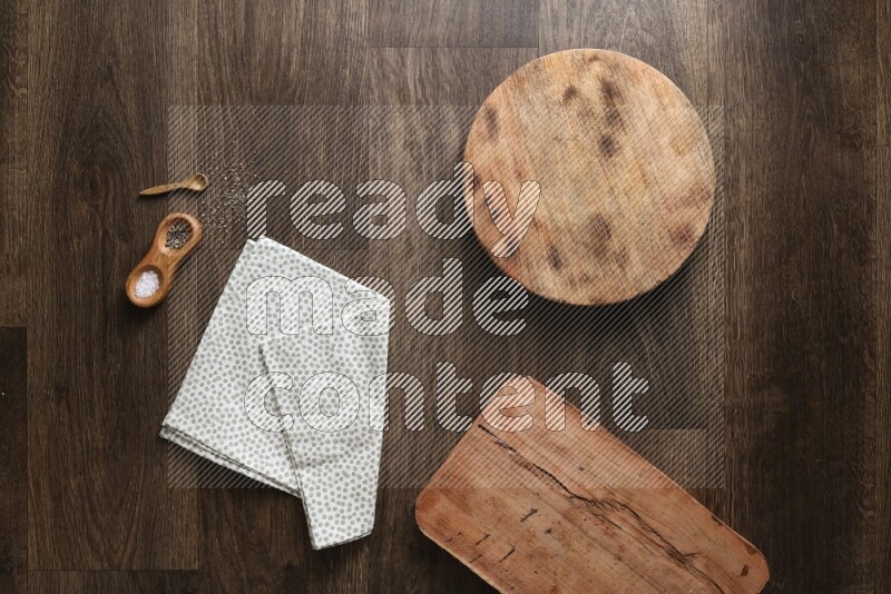 Wooden (chopping boards, spoon, salt and pepper pinch pot), juice jar and a napkin on wooden background
