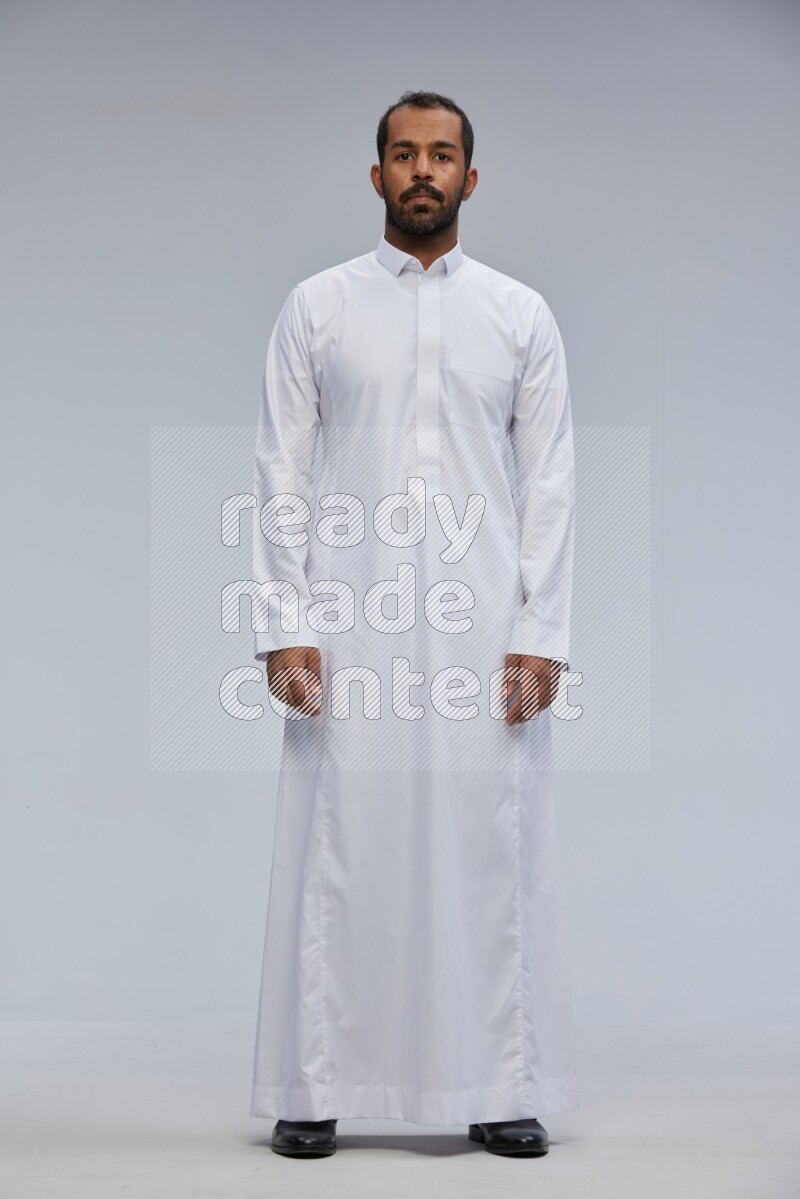Saudi man Wearing Thob standing interacting with the camera on Gray background