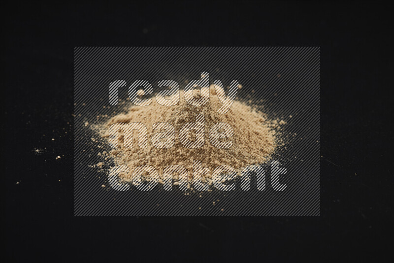 A bunch of ground ginger powder on black background