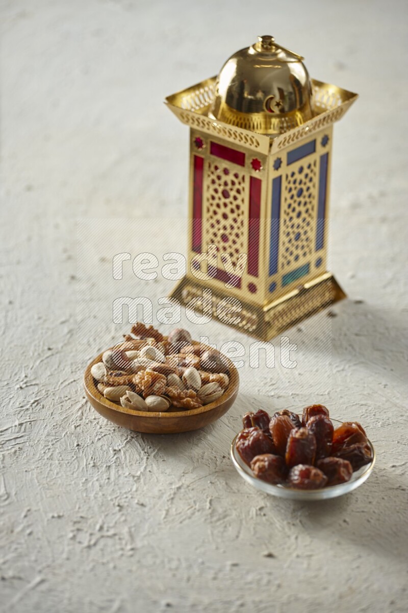 A golden lantern with different drinks, dates, nuts, prayer beads and quran on textured white background