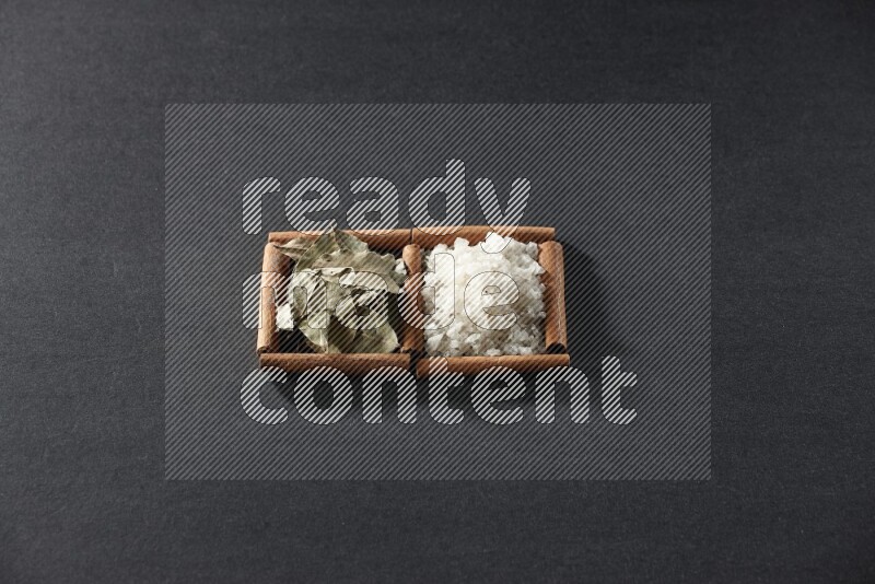 2 squares of cinnamon sticks full of salt and bay laurel on black flooring