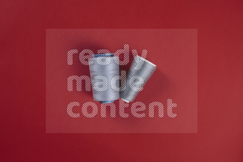 A grey collection of sewing and tailoring tools arranged on a red background