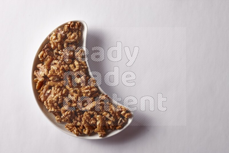 Walnuts in a crescent pottery plate on white background