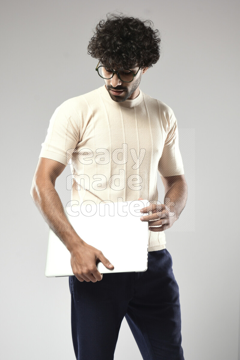 A man wearing casual standing and holding a laptop on white background