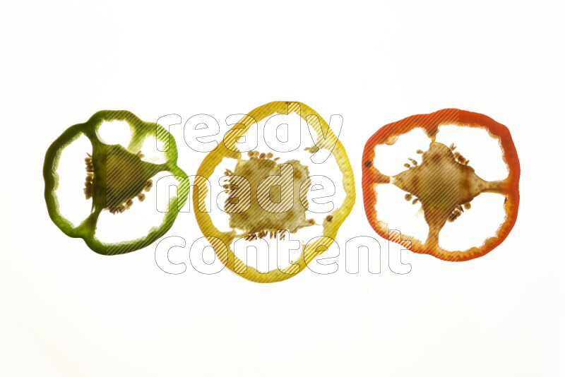 Colored bell pepper slices on illuminated white background