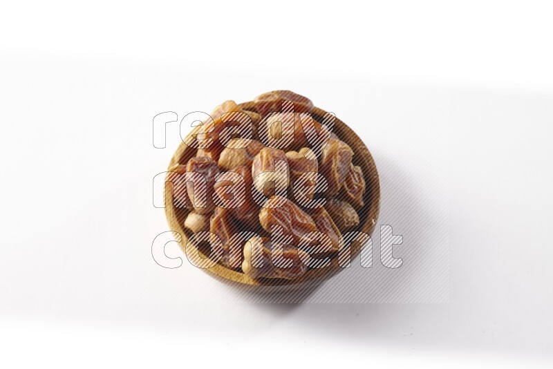 Dates in a wooden bowl on white background