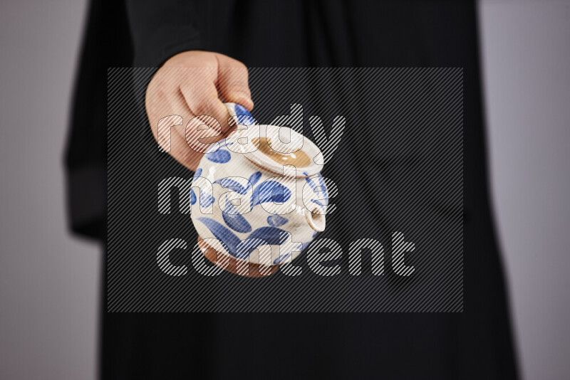 A woman in black abaya holding different pottery essentials in different positions