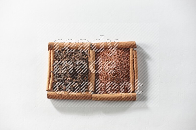 2 squares of cinnamon sticks full of garden cress and cloves on white flooring