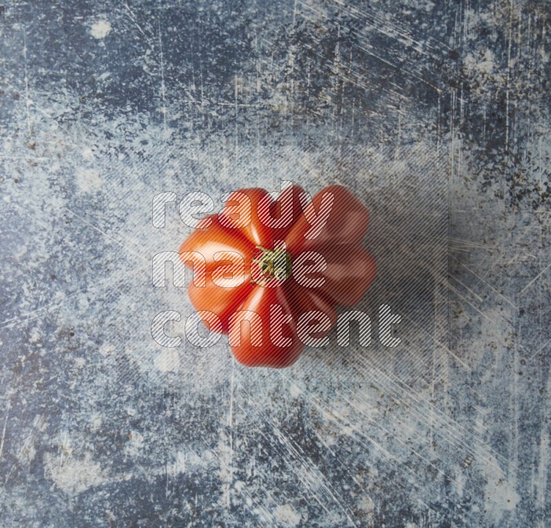 Single Topview Heirloom Tomato on a textured rustic blue background