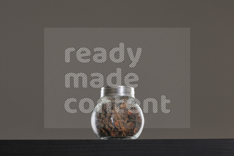 Star anise in a glass jar on black background