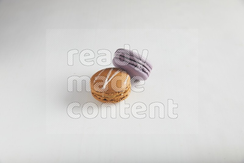 45º Shot of of two assorted Brown Irish Cream, and Purple Blueberry macarons on white background
