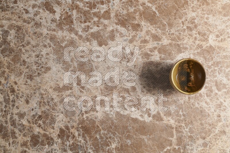A multicolored pottery cup on beige marble background