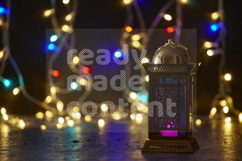 A traditional ramadan lantern surrounded by glowing fairy lights in a dark setup