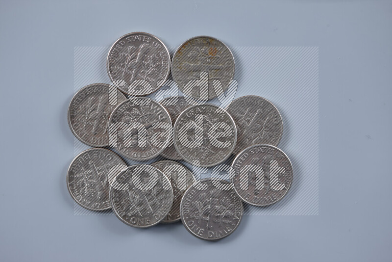 A close-up of scattered United States one dime coins on grey background