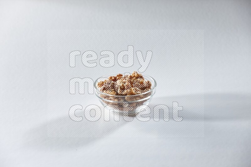 A glass bowl full of peeled walnuts on a white background in different angles