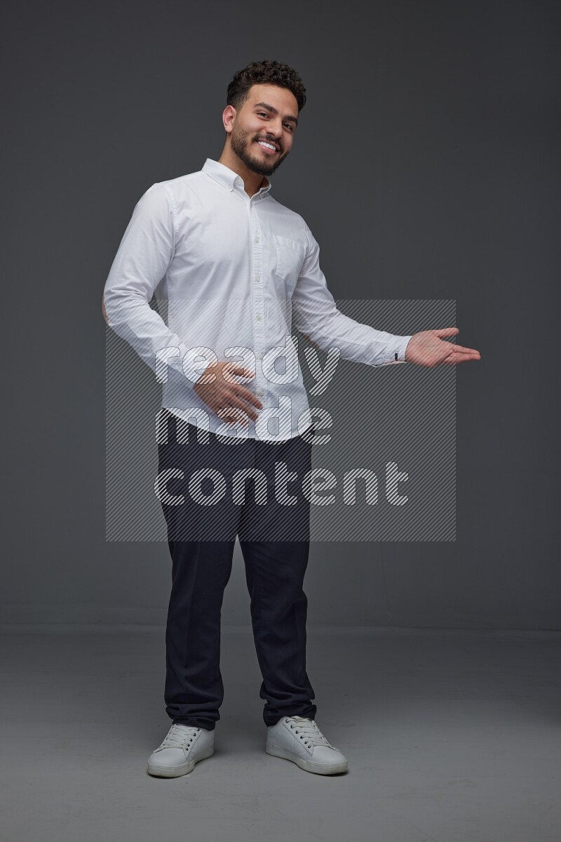 A man wearing smart casual standing and making multi hand gestures eye level on a gray background