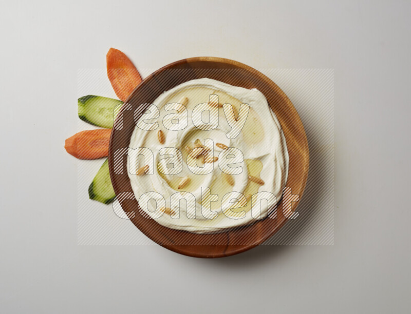 Lebnah garnished with pine nuts in a wooden plate on a white background