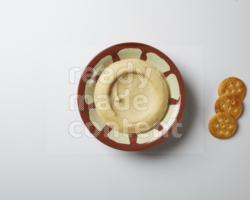 Plain hummus in a traditional plate on a white background