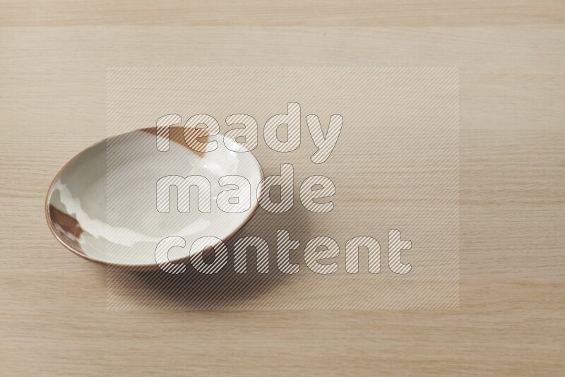 A multicolored pottery plate on light wooden background