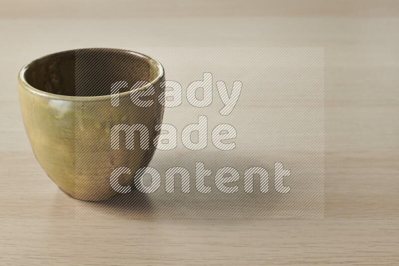 A multicolored pottery bowl on light wooden background