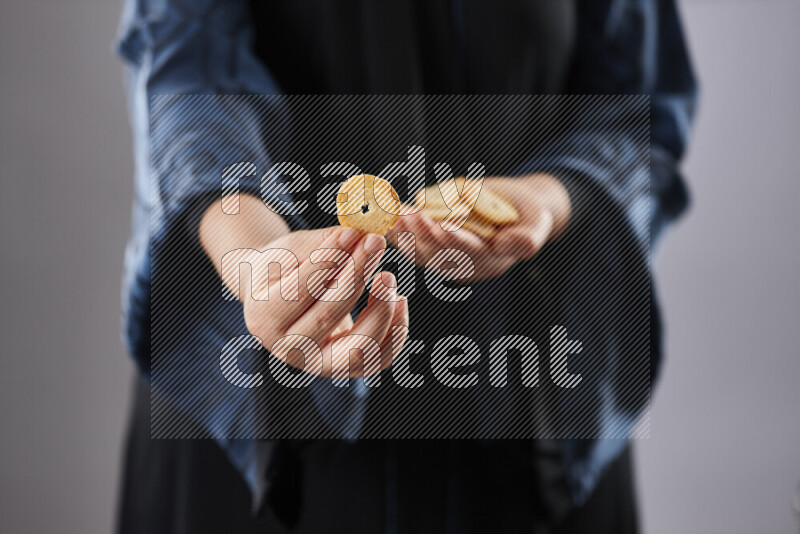 Woman in abaya holding different kinds of snacks in different positions