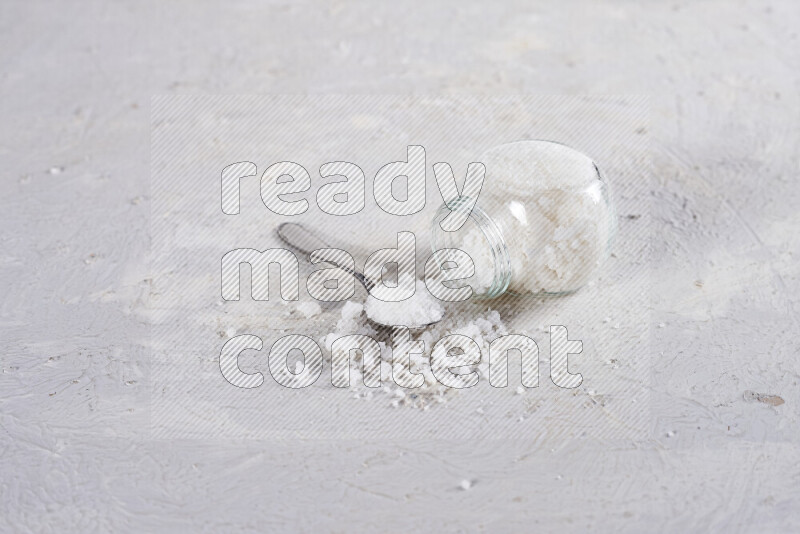 A glass jar full of coarse sea salt crystals on white background