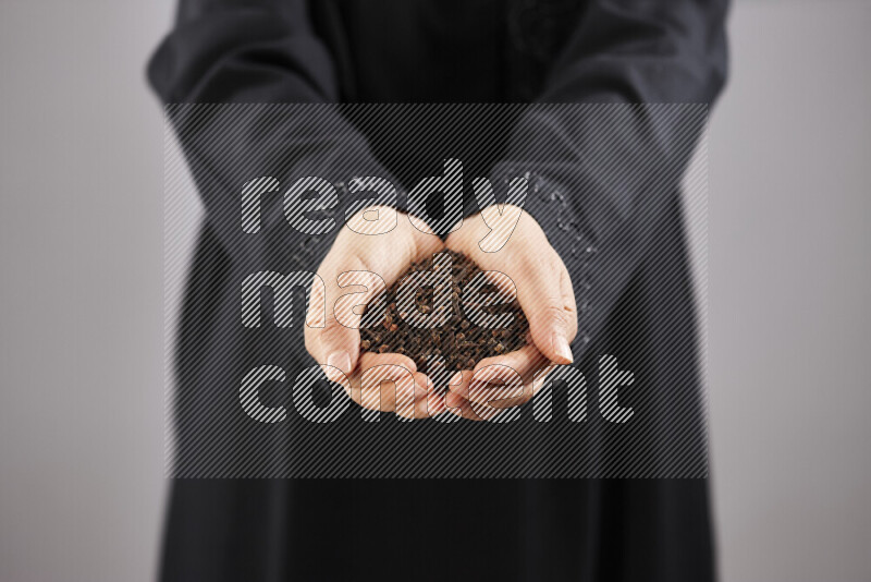 Woman in abaya holding different kinds of spices in different positions