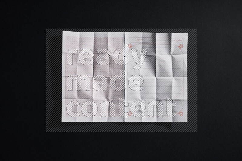 Folded notebook sheet on black background