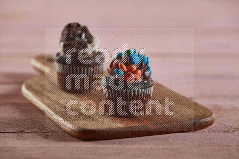 Chocolate mini cupcake topped with m&ms on a wooden board