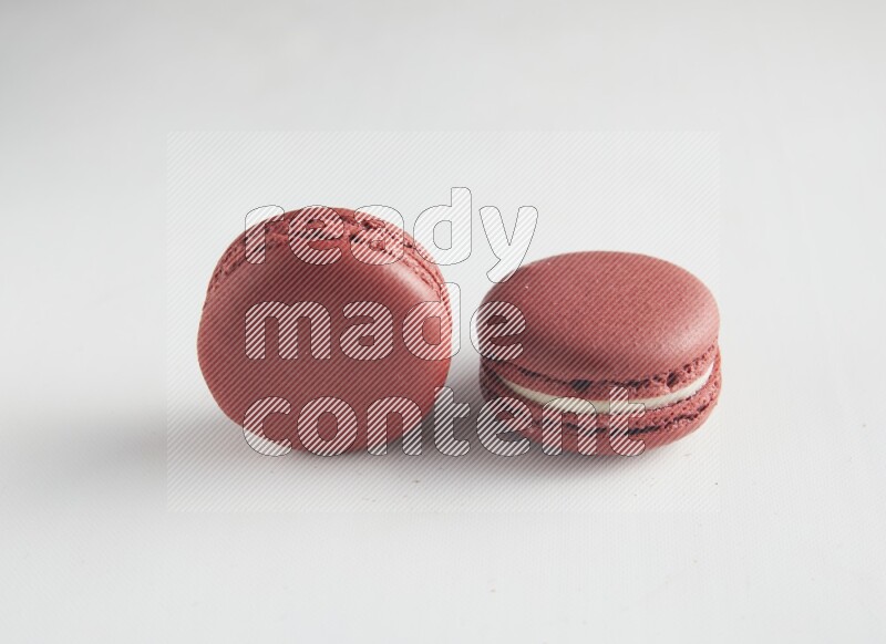 45º Shot of two Red Velvet macarons on white background