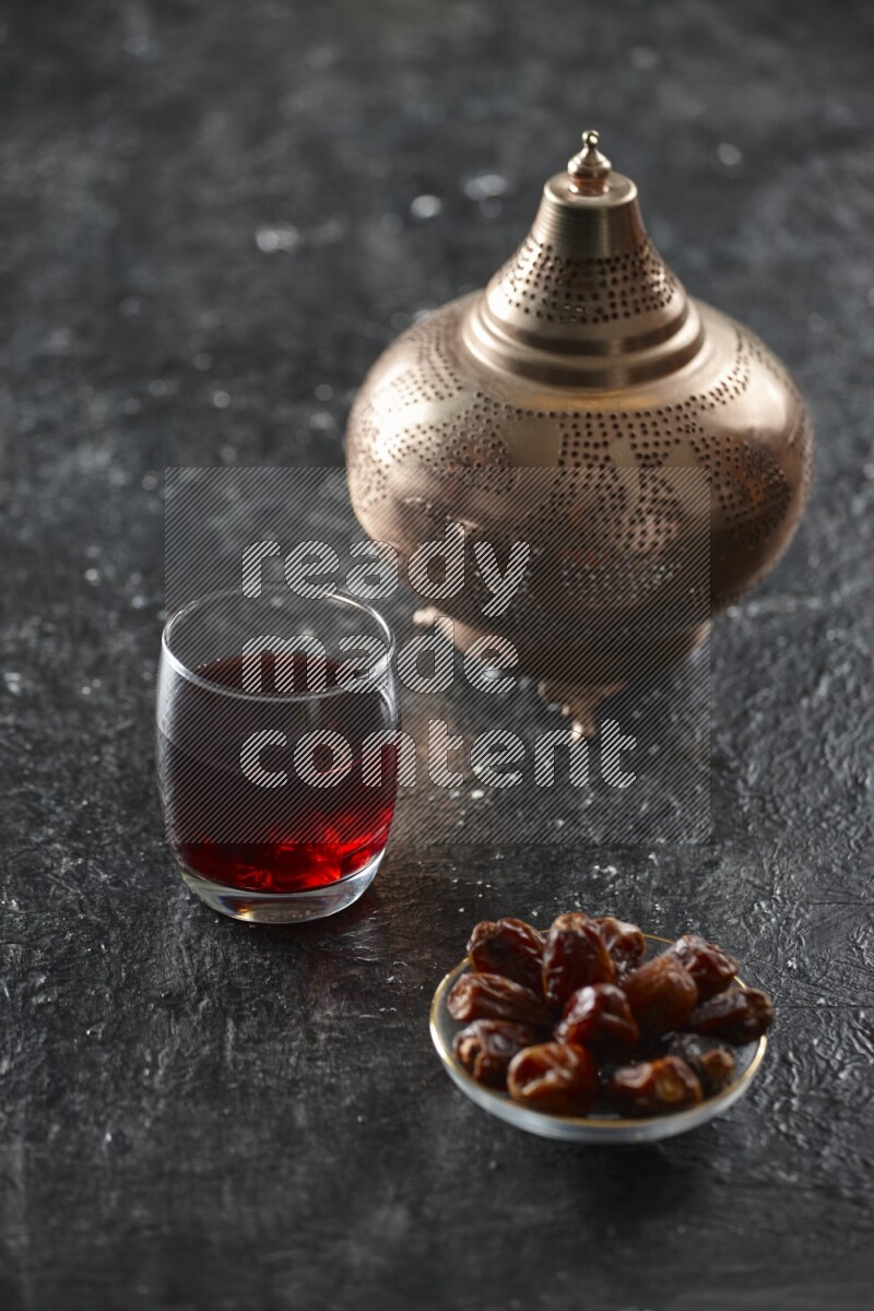 A golden lantern with different drinks, dates, nuts, prayer beads and quran on textured black background