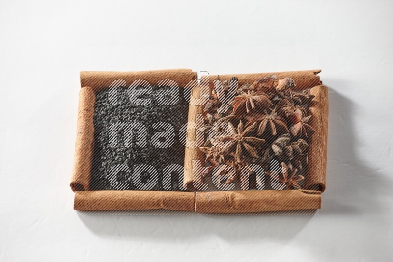 2 squares of cinnamon sticks full of black seeds and star anise on white flooring