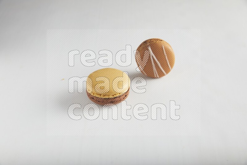 45º Shot of of two assorted Brown Irish Cream, and Yellow, and Brown Chai Latte macarons on white background
