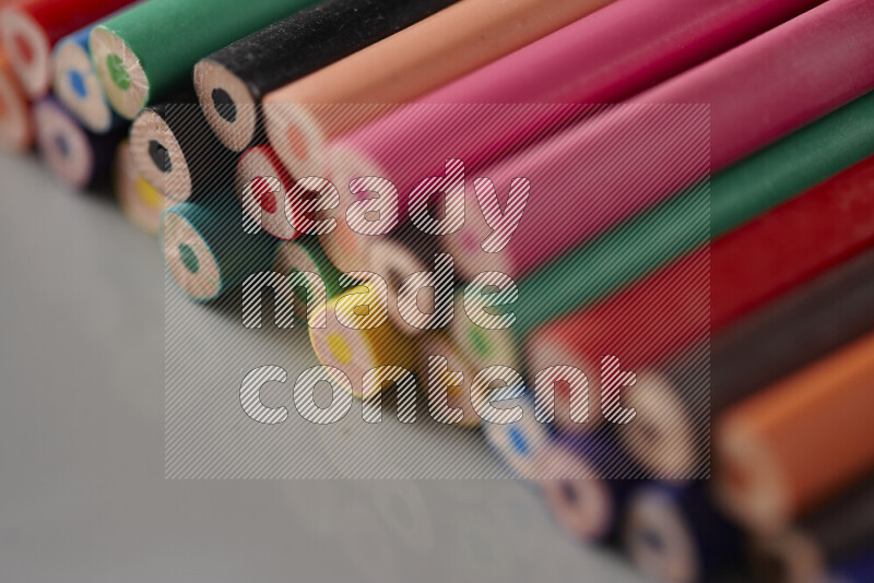 An array of colored pencils on grey background