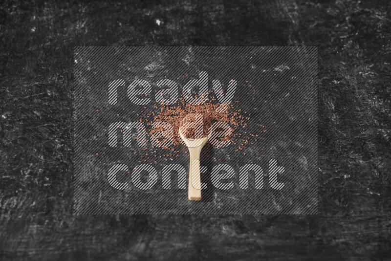 ملعقة خشبية ممتلئة ببذور حب الرشاد محاطه بالبذور علي خلفية سوداء