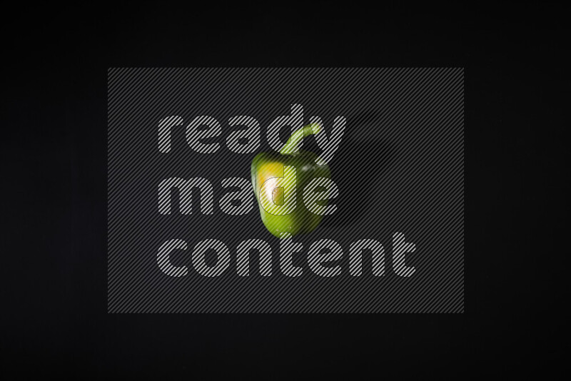 Green bell pepper on black background