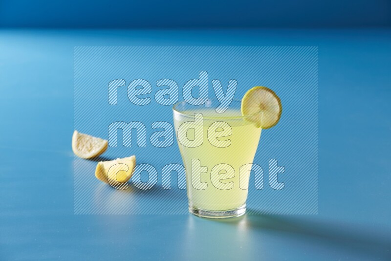 glass of lemon juice with lemon slice  on blue background