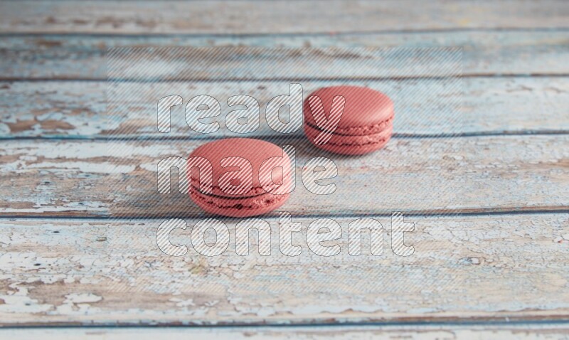 45º Shot of two Pink Raspberry macarons on light blue wooden background